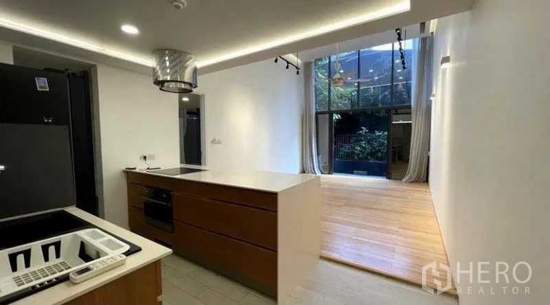 公寓 出租在Watthana, Bangkok - 现代厨房带中岛与嵌入式烤箱，面向采光充足的高窗客厅