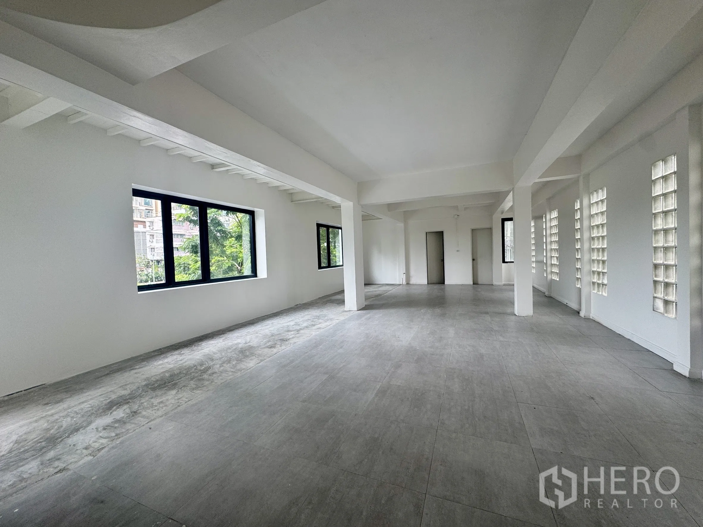 办公空间 出租在Sathon, Bangkok - 长条开放工作区，玻璃砖墙、窗户及两扇内门。