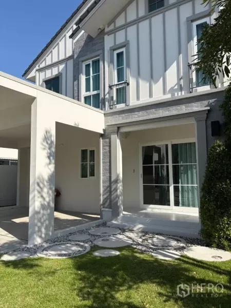 Detached House for rent in Bang Phli, Samut Prakan - Front porch and facade with sliding glass doors and stepping-stone path across the lawn.