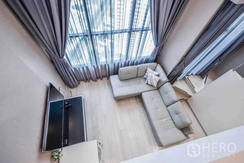 คอนโด ให้เช่าในSathon, Bangkok - มุมมองจากด้านบนของพื้นที่นั่งเล่น เห็นโซฟา ทีวี และหน้าต่างสูงพร้อมผ้าม่าน