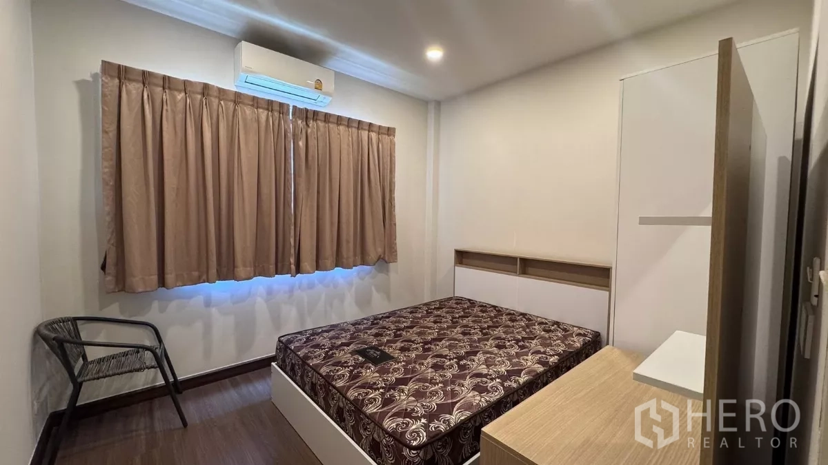 Detached House for rent or sale in Saphan Sung, Bangkok - Bedroom view showing bed, air conditioner and curtained window over wood floors.