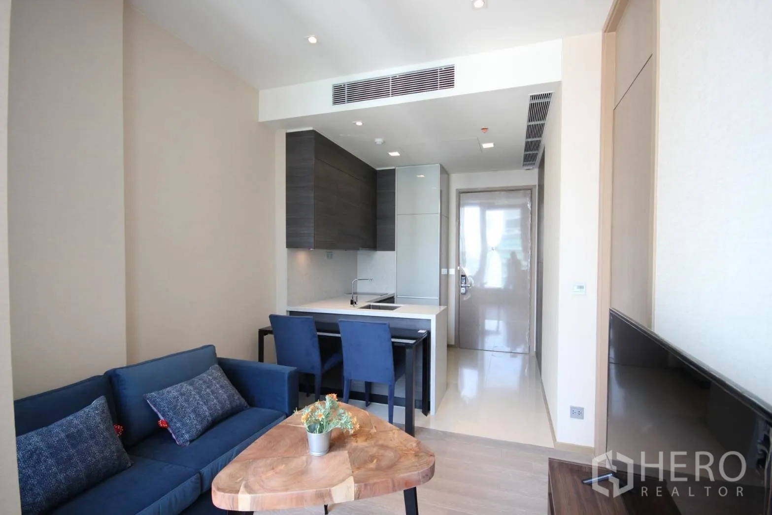 公寓 出租在Watthana, Bangkok - 开放式客厅，蓝色沙发、双人餐桌与紧凑厨房，位于阿索克区域。