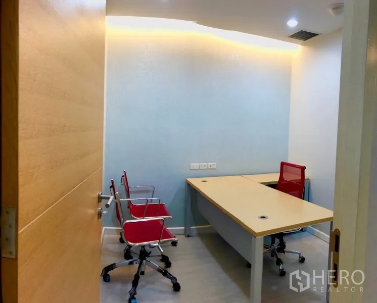 Office Space for rent in Bang Na, Bangkok - Compact manager room with a long worktable, red task chairs and soft cove lighting.
