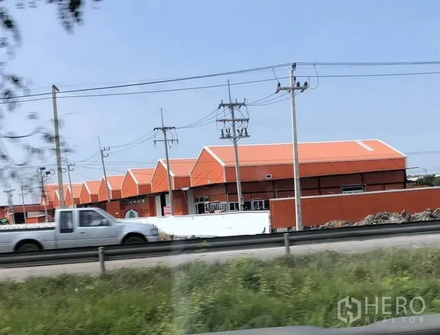 货栈 出租在Pathum Thani - 巴吞他尼Lat Lum Kaeo路旁的橙色屋顶仓库群，临主干道，设有电线与围栏。