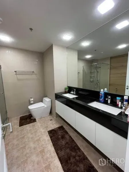 公寓 出售在Pathum Wan, Bangkok - 宽敞卫浴，双洗手台、大镜子、玻璃淋浴间与现代洁具。
