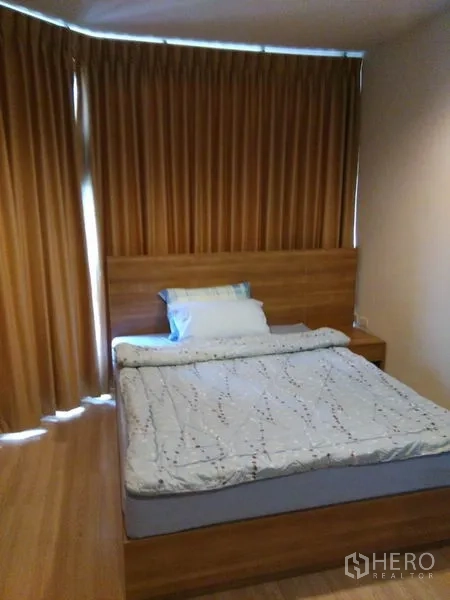 Condominium for rent in Sathon, Bangkok - Simple bedroom with wooden bedframe and full curtains, warm wood flooring.