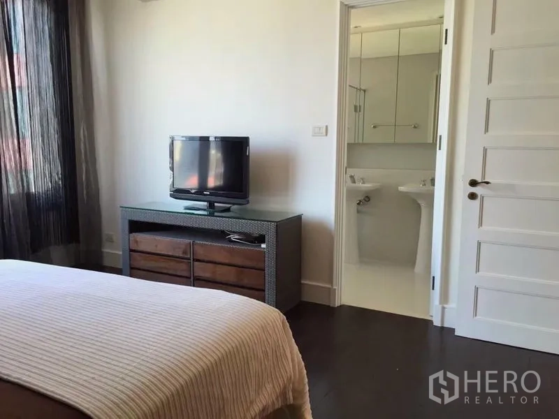 Condominium for rent in Khlong Toei, Bangkok - Bedroom with TV console and an ensuite bathroom visible through the doorway.