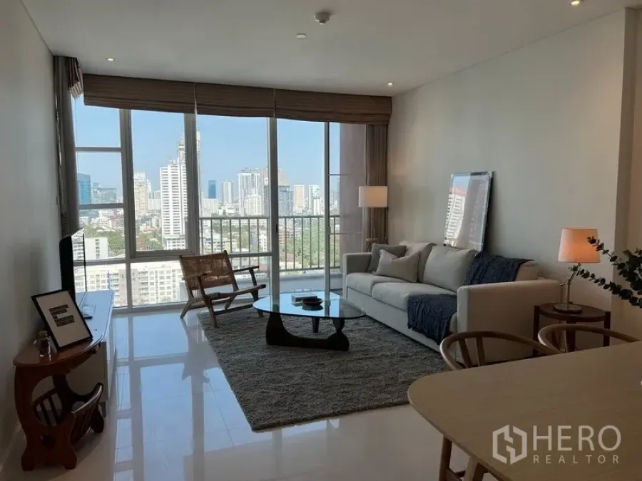 公寓 出租在Watthana, Bangkok - 采光充足的客厅，落地窗与阳台，尽享城市天际线。
