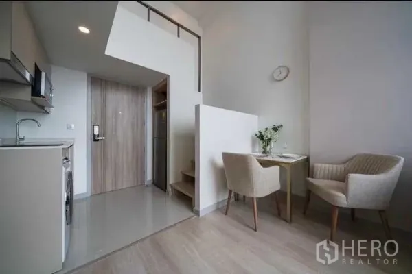 公寓 出租在Sathon, Bangkok - 紧凑厨房与用餐角，位于夹层下方，木质入户门旁。