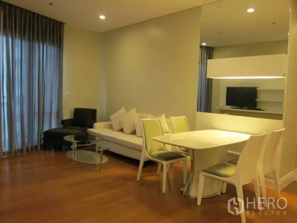 Condominium for rent in Khlong Toei, Bangkok - Bright lounge with floor-to-ceiling curtains, sofa set and glass coffee tables in a modern Bangkok condominium.