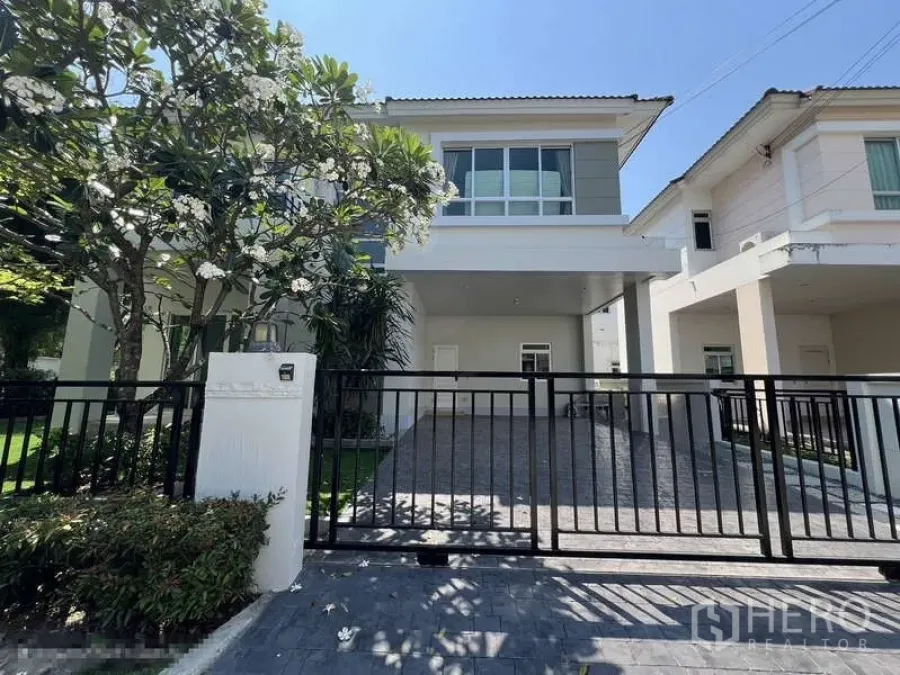 Detached House for rent in Saphan Sung, Bangkok - Front view of a modern two‑storey detached house with black gate, driveway and frangipani tree.