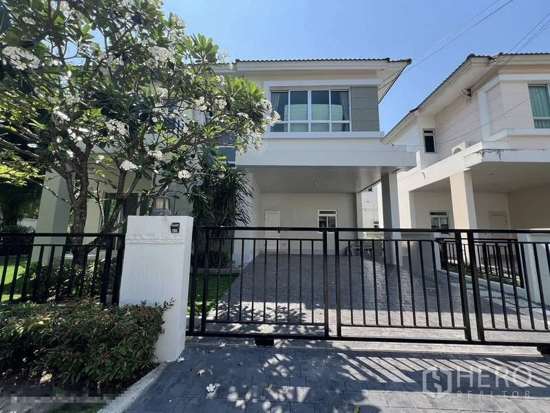 Detached House for rent in Saphan Sung, Bangkok - Front view of a modern two‑storey detached house with black gate, driveway and frangipani tree.