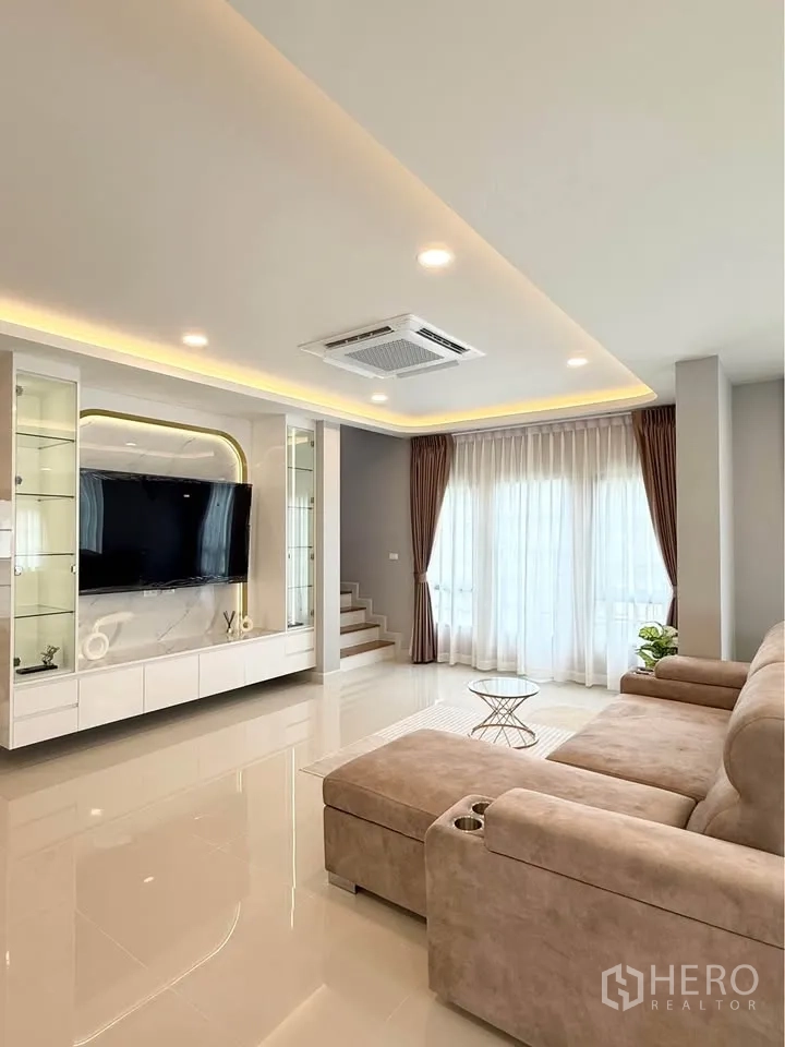 Detached House for rent in Bang Phli, Samut Prakan - Ground-floor living room with built-in TV wall and sectional sofa.