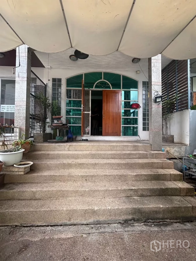 Shophouse for rent in Watthana, Bangkok - Wide front steps leading to an arched glass entrance with solid wooden doors.