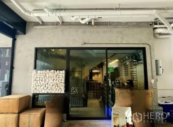 Retail Space for rent in Khlong Toei, Bangkok - Glass-fronted shop entrance with sliding door, concrete walls and visible ceiling ductwork.