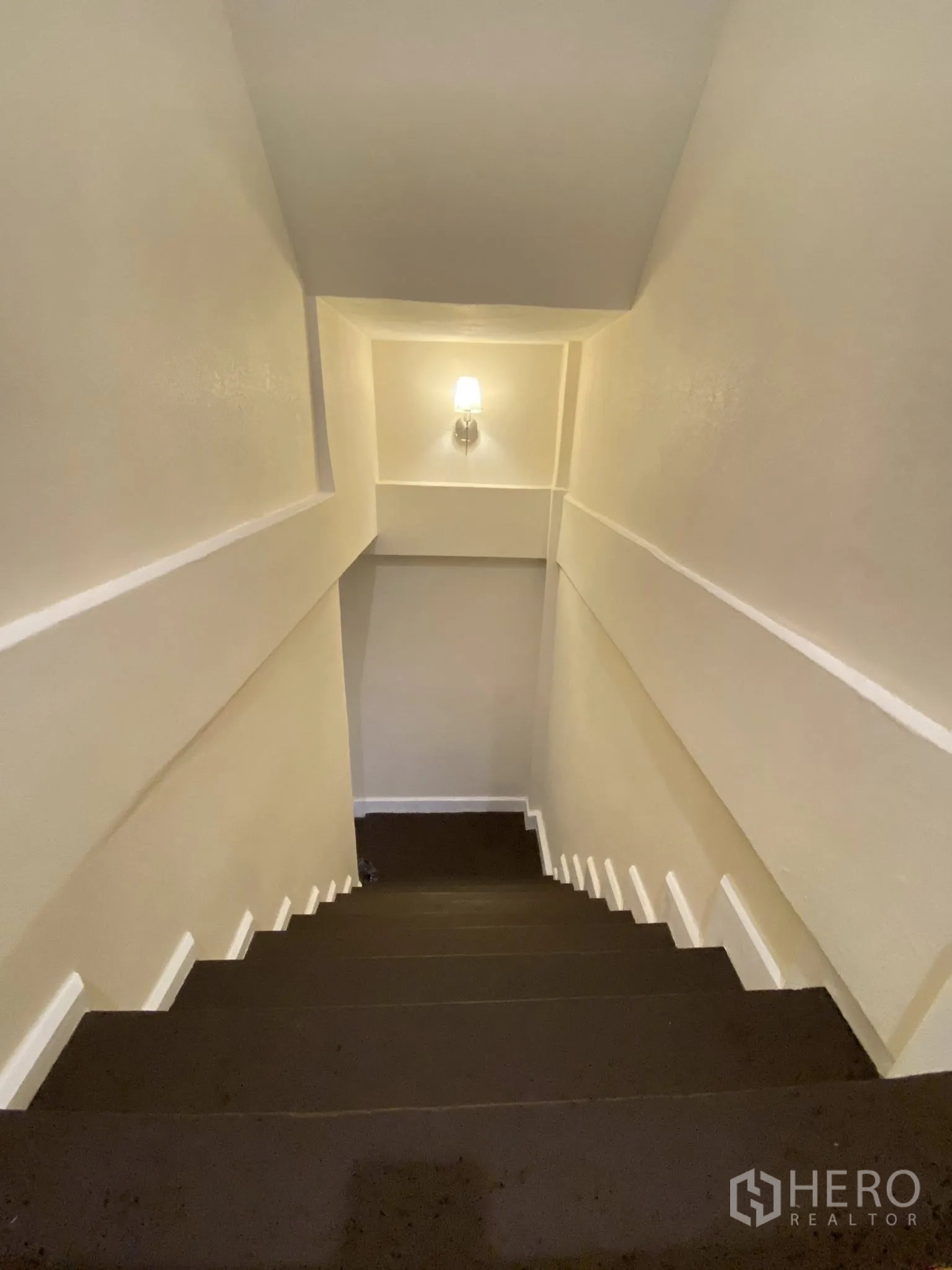 家庭办公室 for rent in Pathum Wan, Bangkok - 明亮的下行楼梯，墙面壁灯与白色装饰线条。