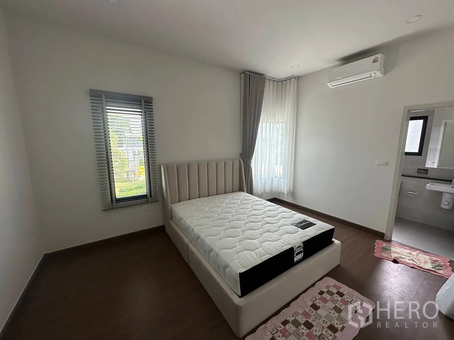 Detached House for rent in Bang Phli, Samut Prakan - Bright bedroom with a double bed, wood flooring, air-conditioning, corner windows and an ensuite bathroom in a detached house in Bang Phli, Samut Prakan.