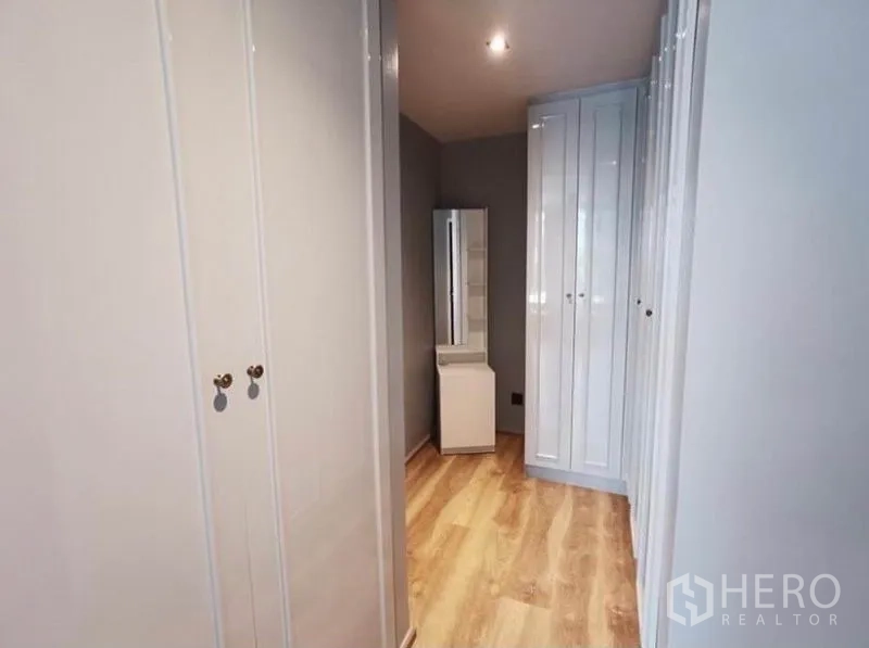 Condominium for rent in Sathon, Bangkok - Walk-in closet corridor with multiple built-in wardrobes and a vanity.