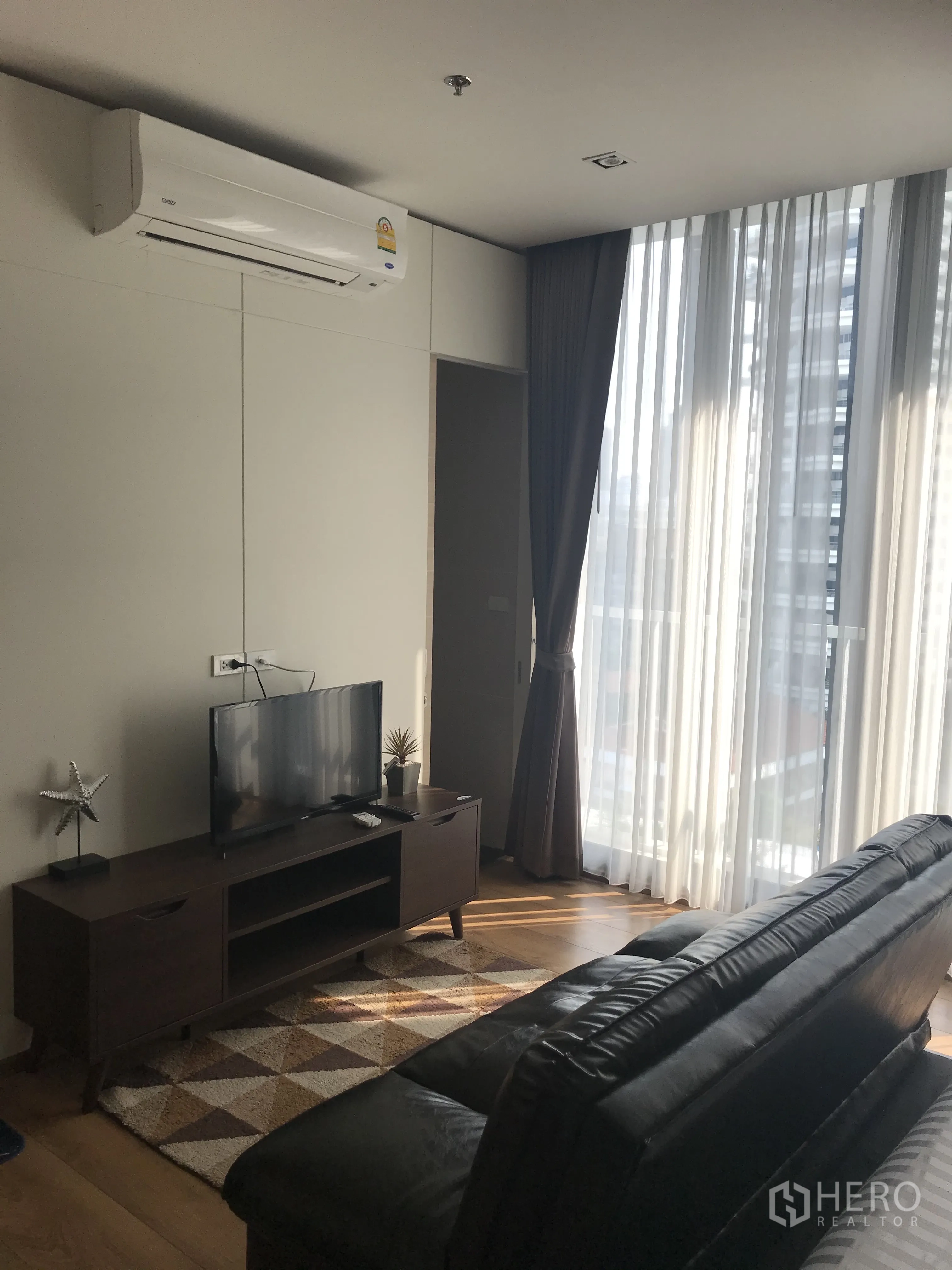 公寓 for sale in Khlong Toei, Bangkok - 起居区有空调、电视柜、皮沙发与明亮窗户。