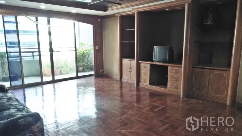 公寓 出售在Watthana, Bangkok - 大型起居室，内置木质柜体，玻璃门通向露台。