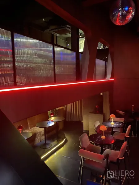 Shophouse for rent in Watthana, Bangkok - Mezzanine lounge with round tables, accent lighting and textured panels.