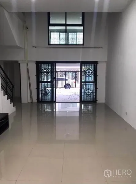 联排别墅 出租在Wang Thonglang, Bangkok - 挑高客厅，推拉玻璃门通向车棚。