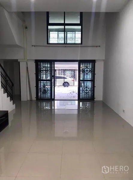 联排别墅 出租在Wang Thonglang, Bangkok - 挑高客厅，推拉玻璃门通向车棚。