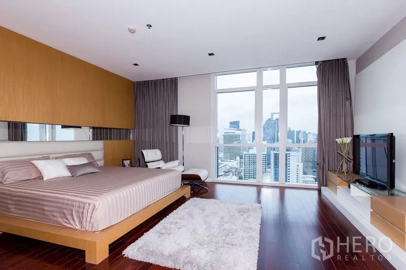 公寓 出租在Pathum Wan, Bangkok - 宽敞主卧，木地板、地毯与高窗城市景。