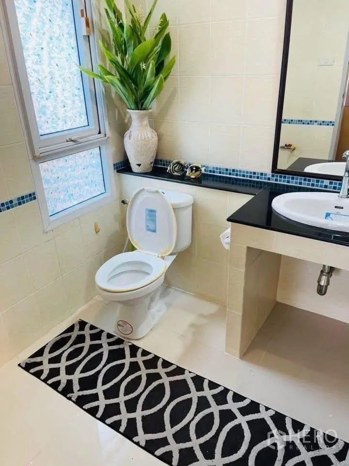 Detached House for rent or sale in Lam Luk Ka, Pathum Thani - Clean tiled bathroom with vanity, mirror and window beside toilet.