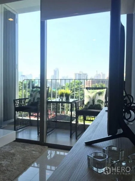 คอนโด ให้เช่าในWatthana, Bangkok - ระเบียงพร้อมชุดโต๊ะเก้าอี้ มองเห็นวิวต้นไม้และเส้นขอบฟ้าเมืองผ่านประตูกระจกบานเลื่อน