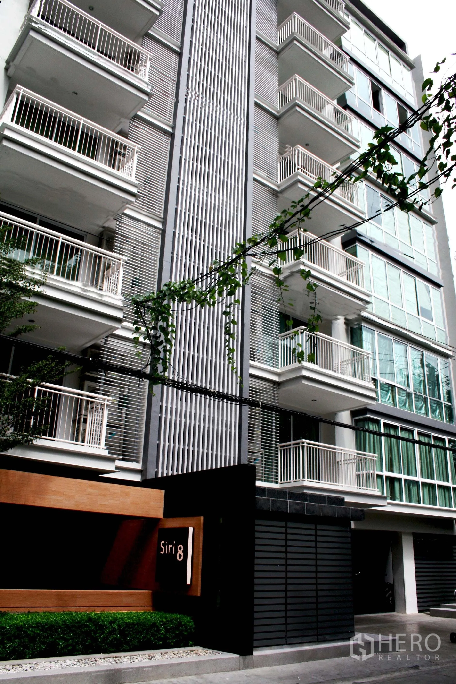 公寓 出租在Khlong Toei, Bangkok - 现代公寓外立面，白色阳台与“Siri 8”入口标识。