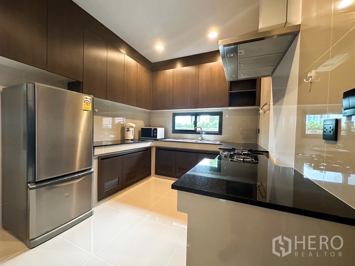 Detached House for rent or sale in Bang Kapi, Bangkok - Alternate view of fitted kitchen showing stone countertops and range hood.