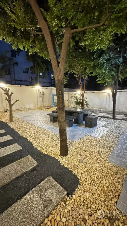 Townhouse for rent or sale in Saphan Sung, Bangkok - Night shot of pebble garden with trees and outdoor table set.