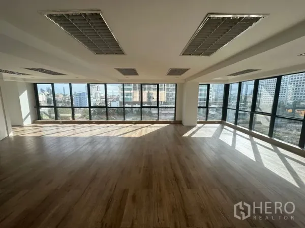 Office Space for rent in Sathon, Bangkok - Spacious office with wraparound glass walls, wooden flooring, and abundant natural light across the workspace.