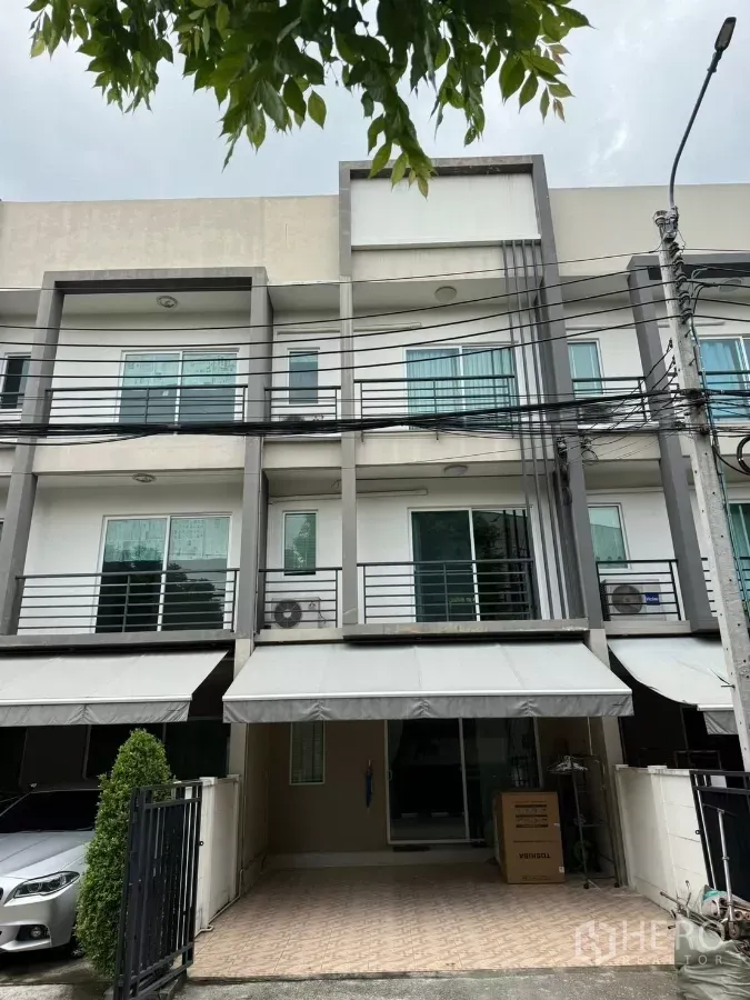 Townhouse for rent in Suan Luang, Bangkok - Modern 3-storey townhouse facade with gated parking and awnings in Suan Luang, Bangkok.