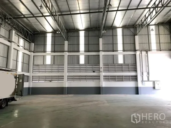 工厂 出租或出售在Samut Prakan - 高挑仓厂内部，钢桁架屋顶、采光带与抛光混凝土地面。
