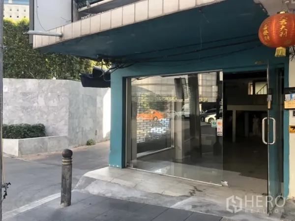 Retail Space for rent in Khlong Toei, Bangkok - Ground-floor glass storefront with wide sliding doors and teal facade at the corner entrance.