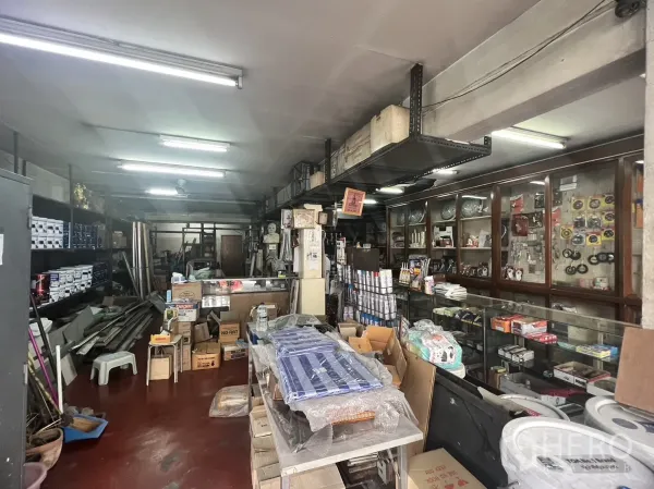 Retail Space for rent in Watthana, Bangkok - Deep retail unit with wall-mounted shelving and glass cabinets for merchandise under strip lights.