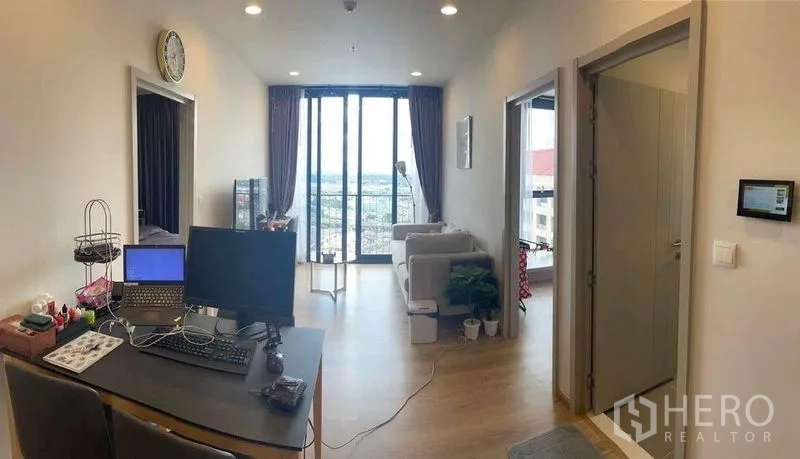 公寓 出租在Khlong Toei, Bangkok - 开放式客厅，带工作区与沙发，通往阳台和城市景观。