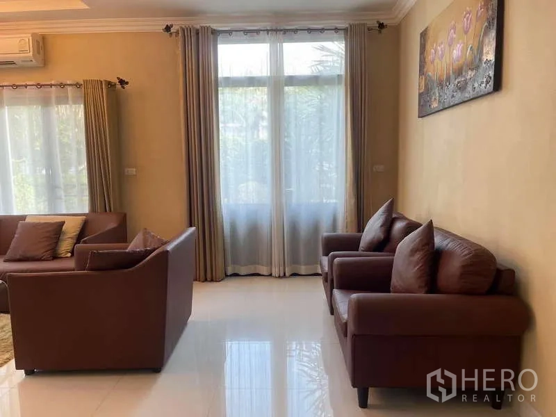 独立式住宅 出租在Mueang Nonthaburi, Nonthaburi - 靠大窗的休闲角，双人扶手椅与米色窗帘。