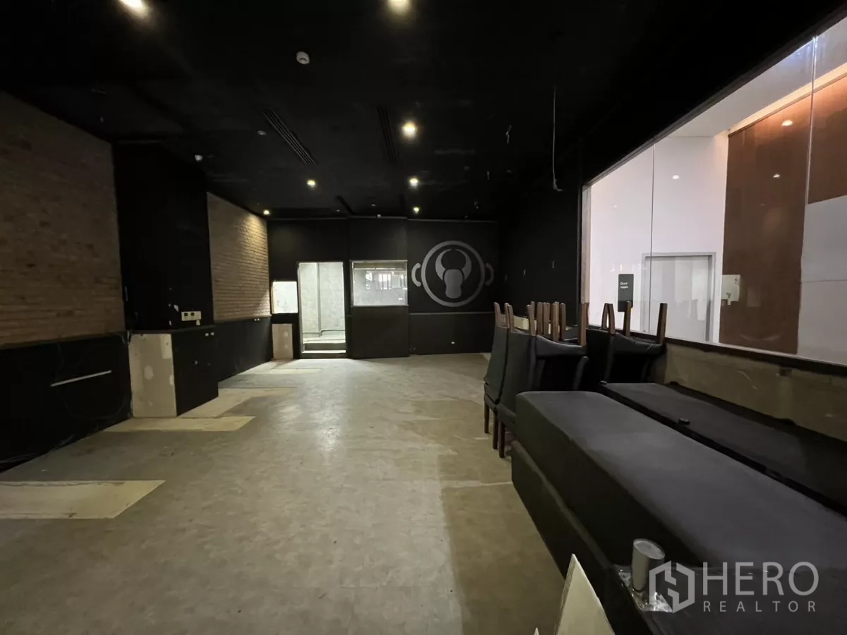 零售空间 出租 - 宽敞用餐/展示区，黑色天花、砖纹装饰墙及厨房观景窗。