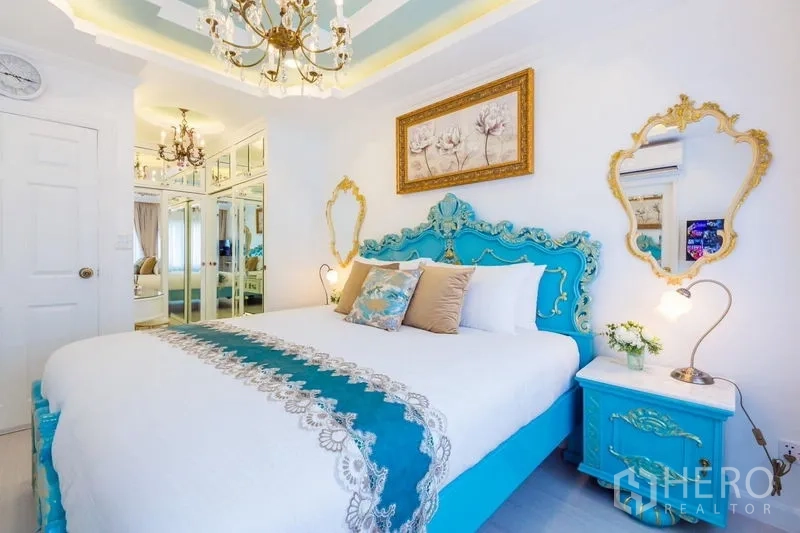 Townhouse for rent in Lat Phrao, Bangkok - Guest bedroom with turquoise baroque bed, mirrored wardrobe, chandeliers and soft ambient lighting.
