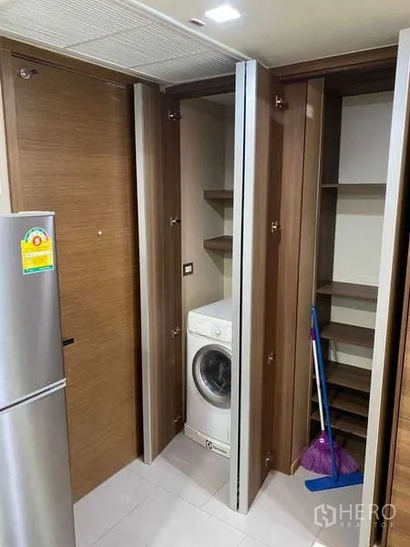 Condominium for rent in Bang Rak, Bangkok - Laundry cabinet with front-loading washing machine and shelving.