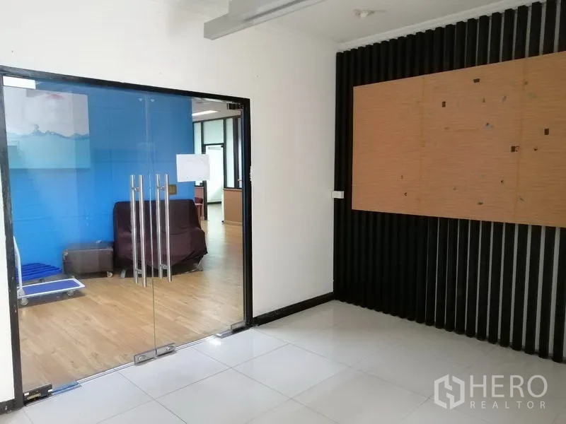 办公空间 出租在Bueng Kum, Bangkok - 玻璃双开门通向木地板办公室，蓝色特色墙与座位区。