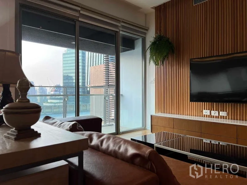 คอนโด ให้เช่าในWatthana, Bangkok - ห้องนั่งเล่นผนังทีวี ประตูกระจกบานเลื่อนออกสู่ระเบียงวิวเมือง
