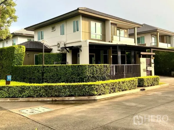 联排别墅 出售在Bang Khae, Bangkok - 角落地块外观，整齐绿篱与宽阔社区道路。