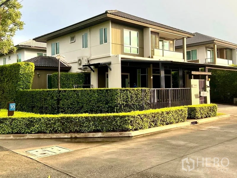 联排别墅 出售在Bang Khae, Bangkok - 角落地块外观，整齐绿篱与宽阔社区道路。