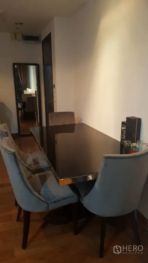 公寓 出租在Pathum Wan, Bangkok - 现代公寓内的用餐角：黑色玻璃餐桌、软包餐椅与木地板