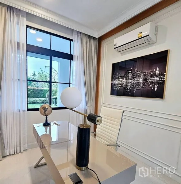 Detached House for rent or sale in Saphan Sung, Bangkok - Quiet home office with large window, sleek desk and cityscape artwork.