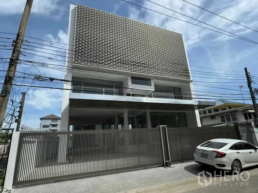 Home Office for rent or sale - Street view of a modern building with a perforated screen facade and gated entry.
